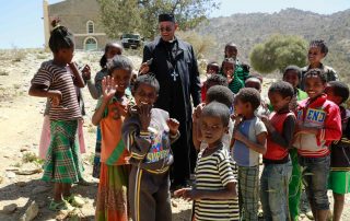 Bispo e crianças em igreja na fronteira da Etiópia