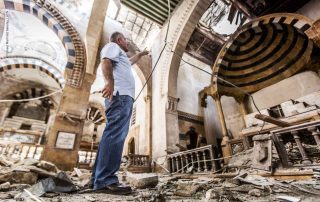 Homem aponta a destruição em meio às ruínas da catedral católica armênia severamente danificada durante a guerra