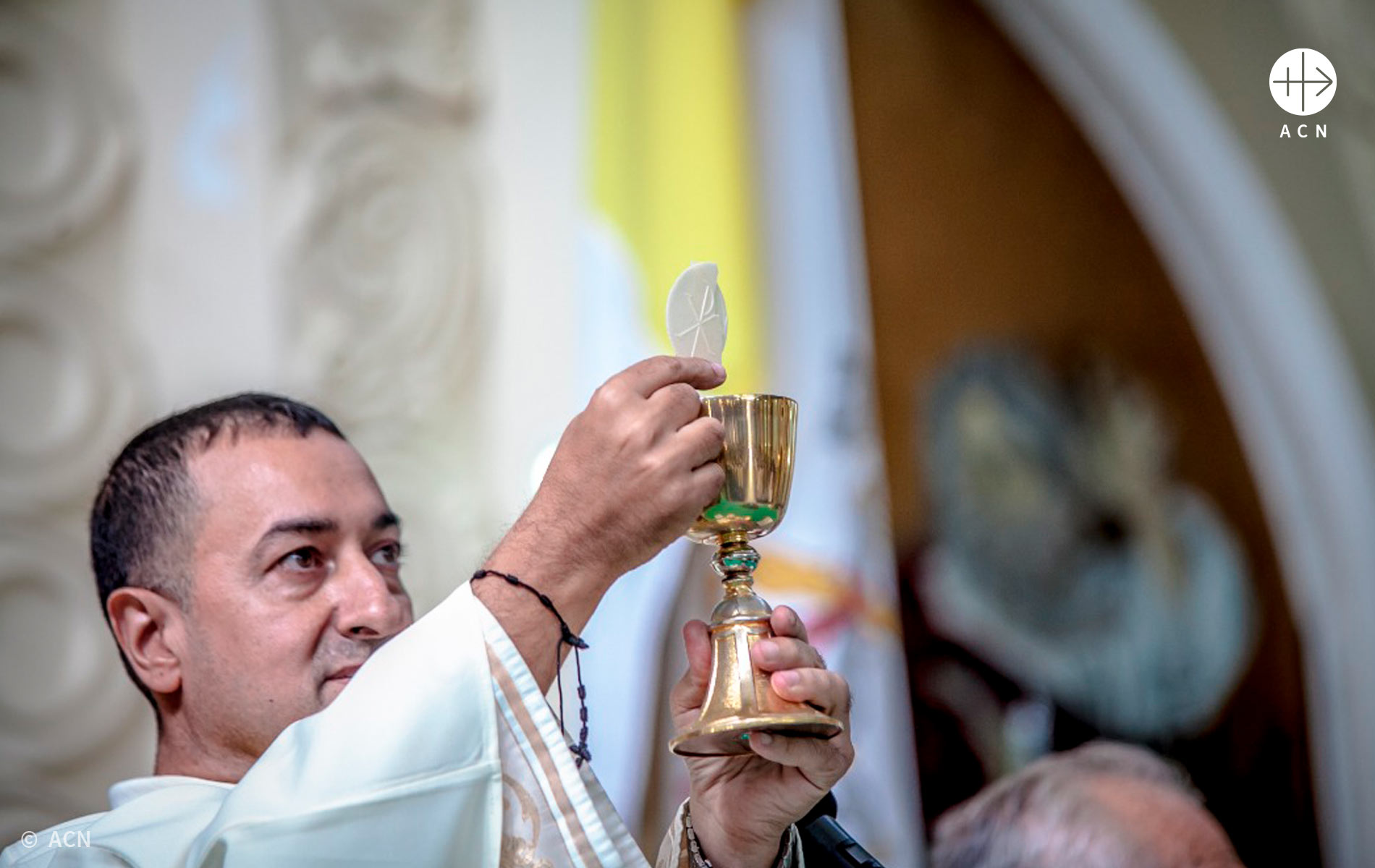 Foto de sacerdote erguendo a Eucaristia